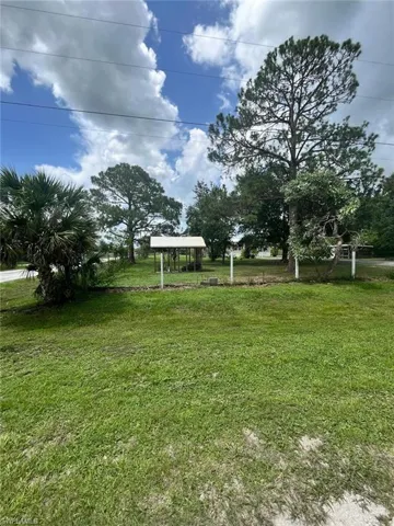 View of green lawn with a gazebo and a detached carport