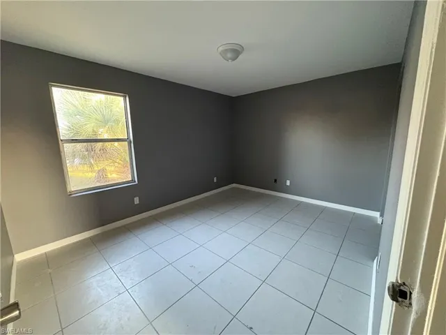 Unfurnished room with baseboards and light tile patterned flooring