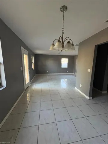 Unfurnished dining area with light tile patterned floors and a chandelier