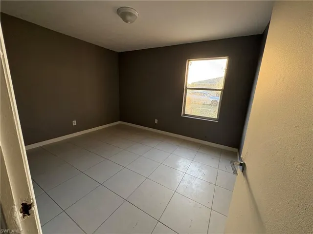 Spare room featuring baseboards and light tile patterned flooring