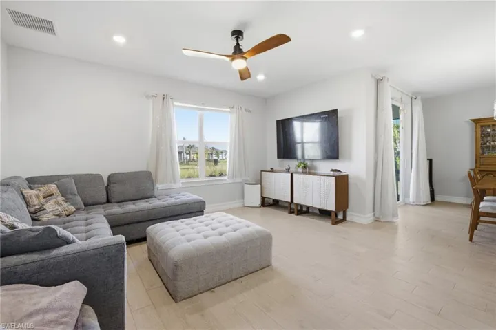 Living area with a ceiling fan, light wood-style flooring, and recessed lighting