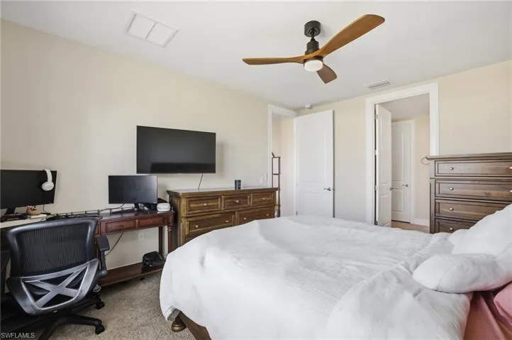 Bedroom featuring a desk, ceiling fan, and light colored carpet