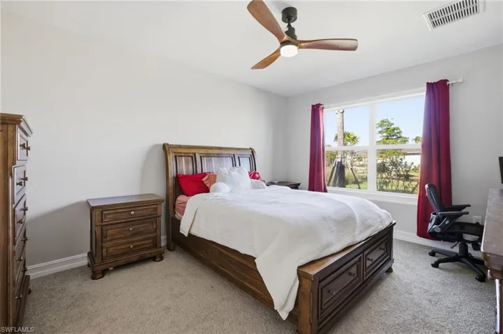 Bedroom featuring light colored carpet, a ceiling fan, and an office area