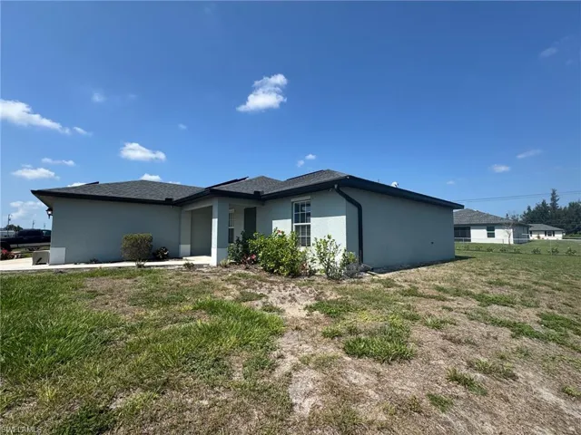 View of front of home featuring roof mounted solar panels, concrete driveway, a garage, stucco siding, and a residential view