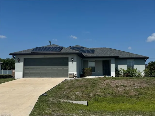 Property entrance with stucco siding, solar panels, and roof with shingles