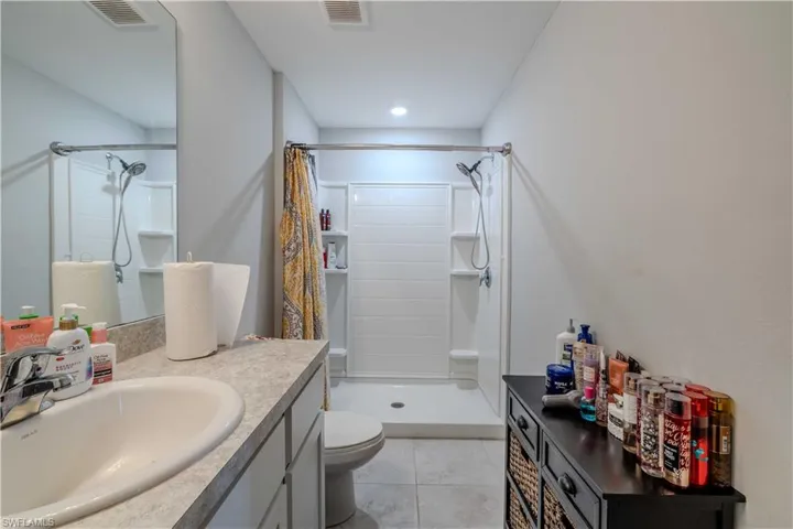 Bathroom with a stall shower, vanity, toilet, and tile patterned flooring