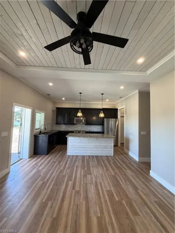 Kitchen featuring wood ceiling, a kitchen island, decorative light fixtures, refrigerator, and ceiling fan