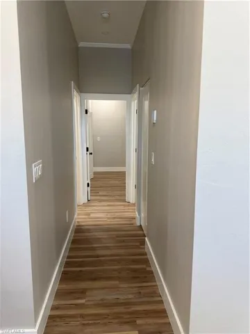 Hallway with wood finished floors and crown molding