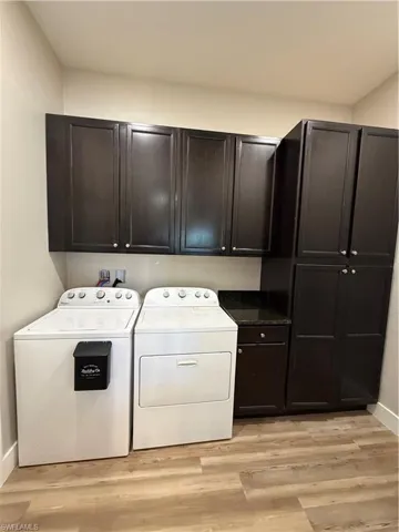 Laundry room featuring cabinet space, washer and clothes dryer, and light wood finished floors