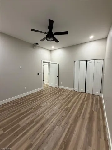 Unfurnished bedroom with a closet, dark wood finished floors, a ceiling fan, and recessed lighting