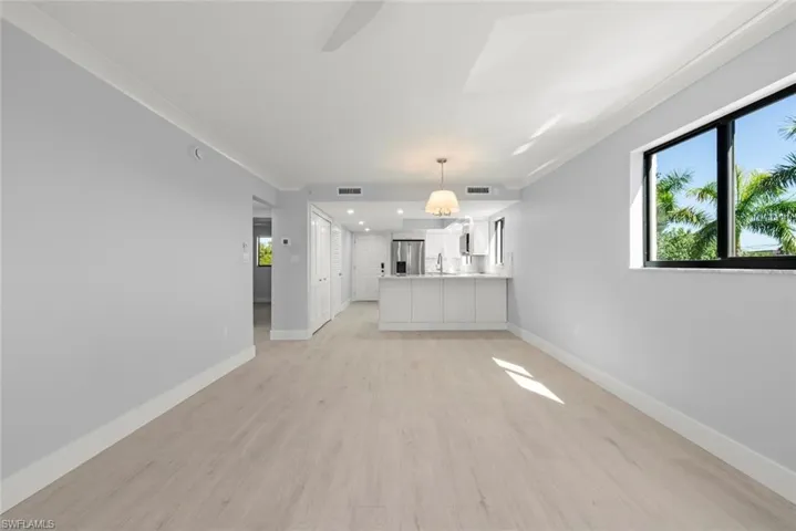 Unfurnished living room with ornamental molding, light wood finished floors, and a ceiling fan