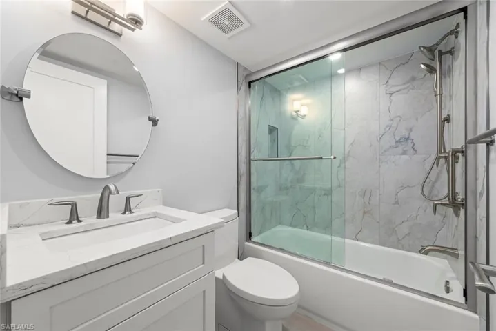 Bathroom featuring vanity and shower / bath combination with glass door