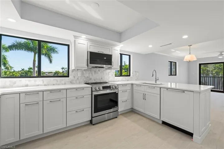 Kitchen with backsplash, stainless steel appliances, healthy amount of natural light, and a peninsula