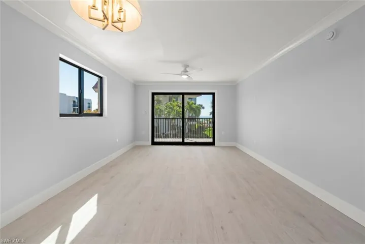 Empty room featuring ornamental molding, plenty of natural light, light wood-type flooring, and ceiling fan