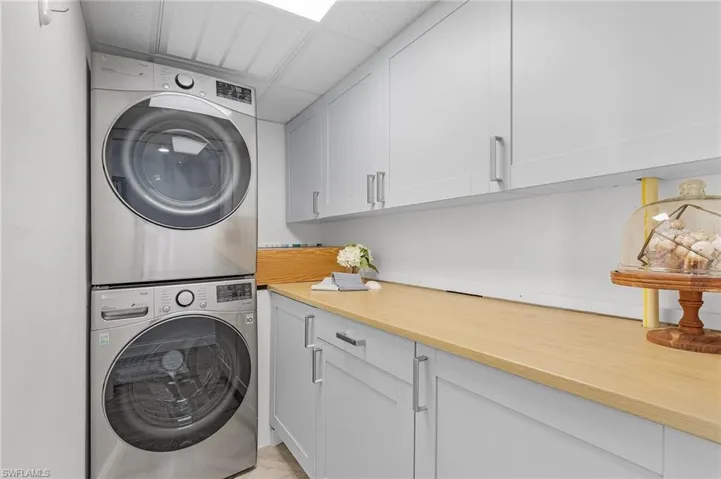 Laundry area with cabinets and stacked washing maching and dryer. PLenty of room for extra storage and folding space.