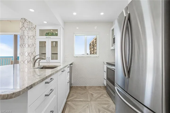 Kitchen featuring a wealth of natural light, white cabinetry, and appliances with stainless steel finishes