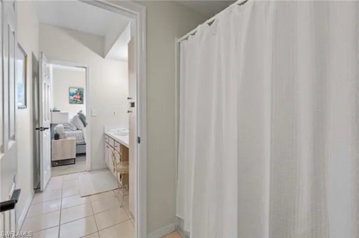 Ensuite bathroom featuring a shower with curtain, vanity, and light tile patterned floors