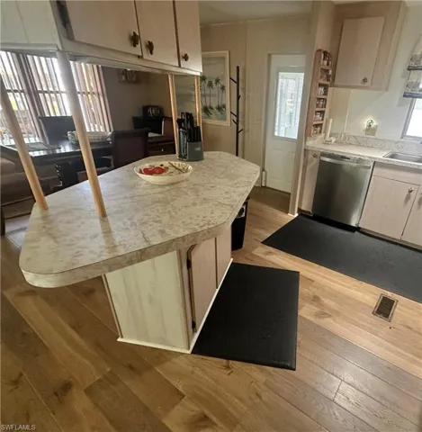 Kitchen featuring stainless steel dishwasher, light wood-style floors, light countertops, and a sink