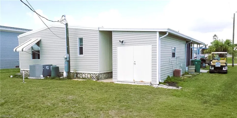 Rear view of property featuring a lawn and central AC unit