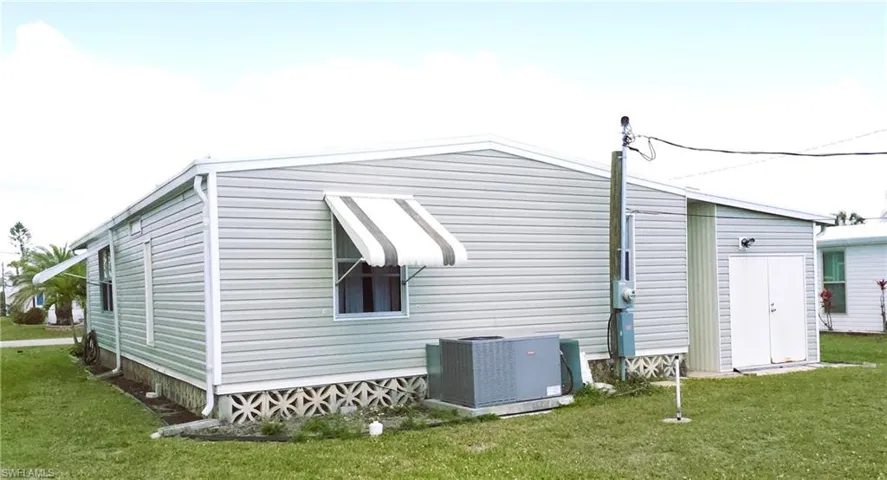 View of side of home featuring cooling unit and a yard