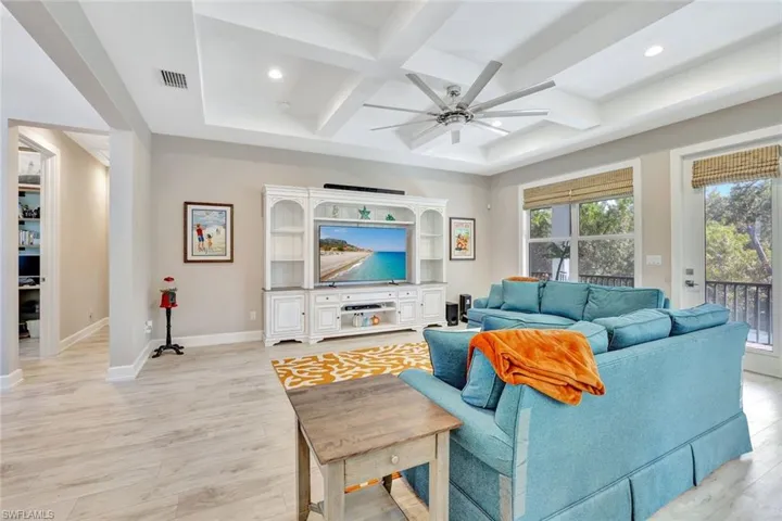 Living area featuring visible vents, a ceiling fan, coffered ceiling, light wood-style floors, and baseboards
