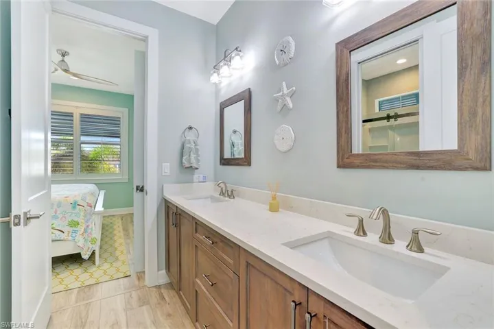 Bathroom with a sink, connected bathroom, a ceiling fan, and double vanity