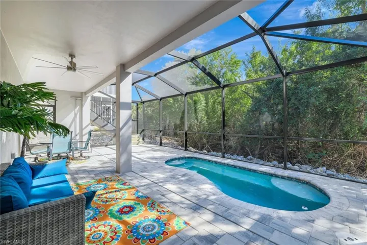 Pool with ceiling fan, glass enclosure, and a patio