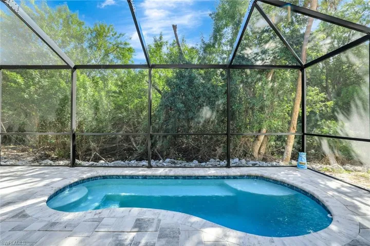 View of swimming pool with glass enclosure and a patio