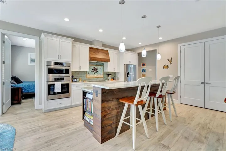 Kitchen with decorative backsplash, light countertops, white cabinets, and stainless steel appliances