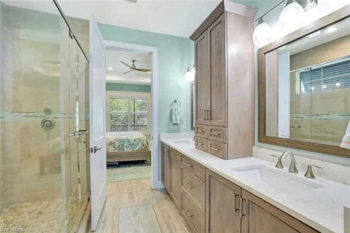 Ensuite bathroom with double vanity, a stall shower, ensuite bath, a ceiling fan, and a sink