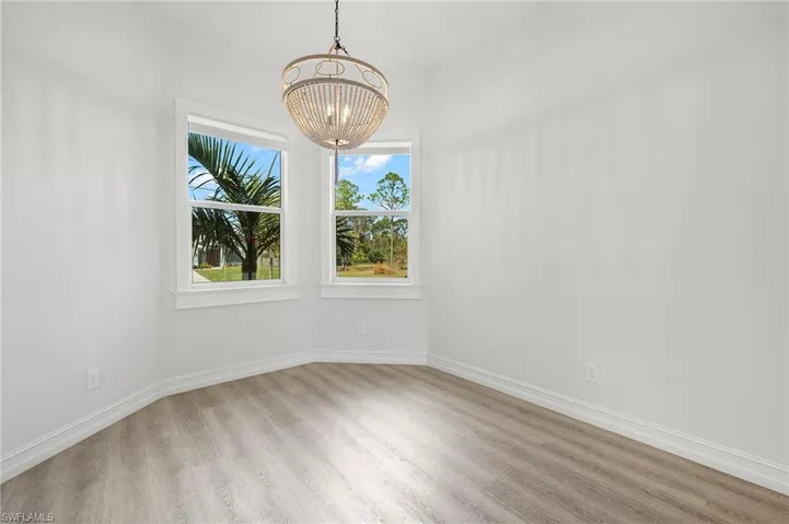 Empty room featuring light wood-type flooring and an inviting chandelier