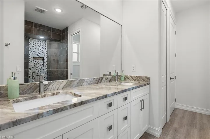 Bathroom with wood-type flooring, a tile shower, and vanity