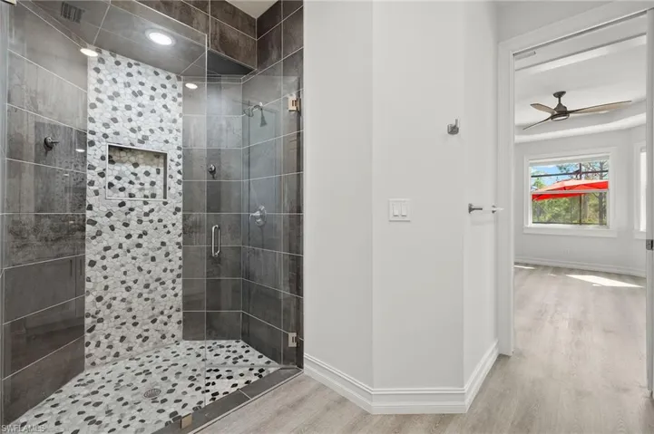 Bathroom with walk in shower, hardwood / wood-style floors, and ceiling fan