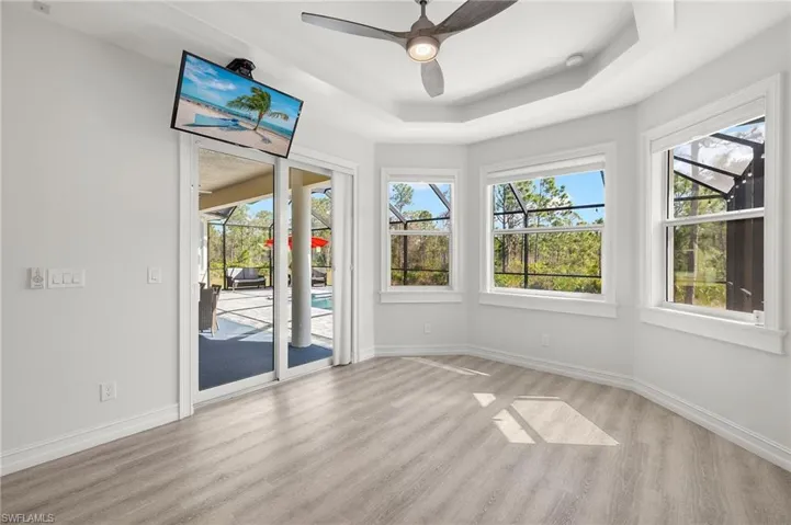 Unfurnished sunroom with a healthy amount of sunlight, ceiling fan, and a raised ceiling
