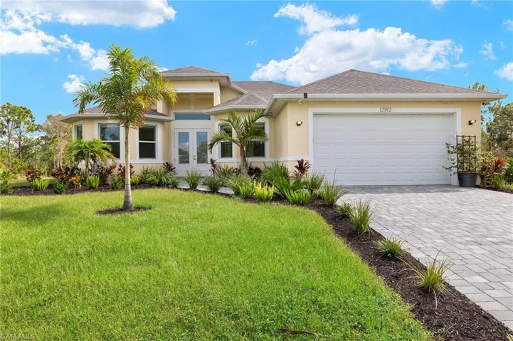 View of front of house with french doors, a garage, and a front lawn