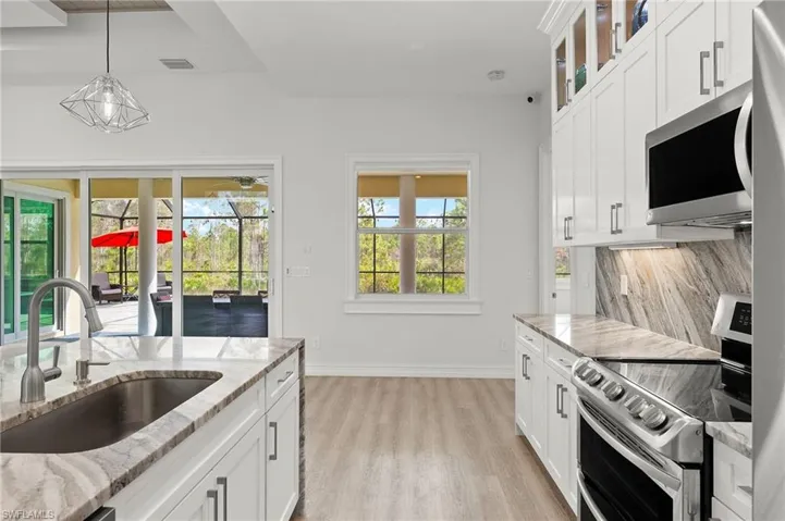 Kitchen with light stone countertops, appliances with stainless steel finishes, sink, and white cabinets