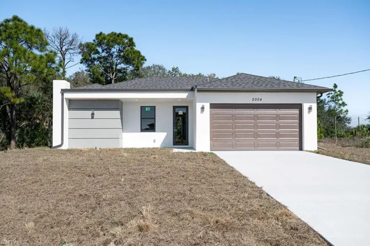 View of front of home featuring a garage, driveway, stucco siding, and a shingled roof