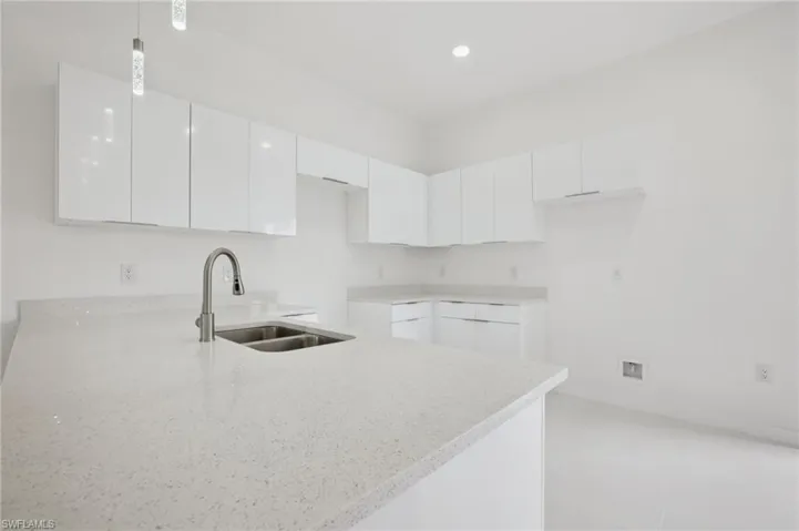 Kitchen featuring white cabinetry, light stone counters, modern cabinets, a peninsula, and recessed lighting