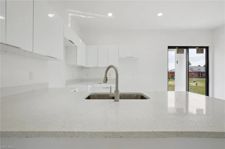 Kitchen featuring light stone counters, white cabinets, modern cabinets, recessed lighting, and a peninsula