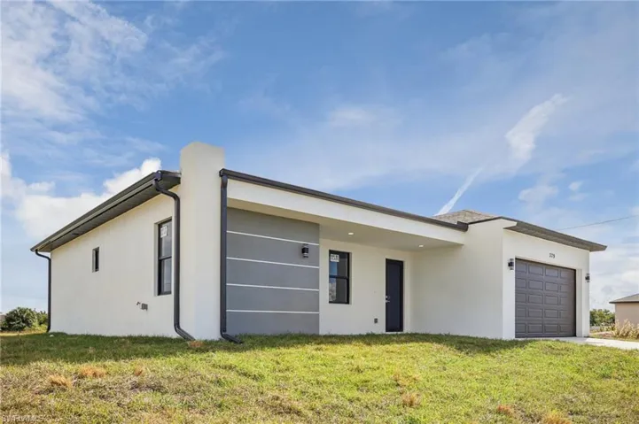Contemporary home featuring stucco siding, an attached garage, and a front yard