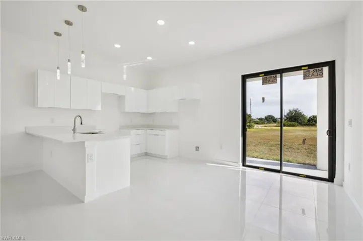 Kitchen with white cabinets, a peninsula, decorative light fixtures, recessed lighting, and modern cabinets