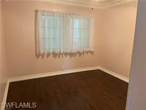 Spare bedroom featuring hardwood / wood-style floors and crown molding