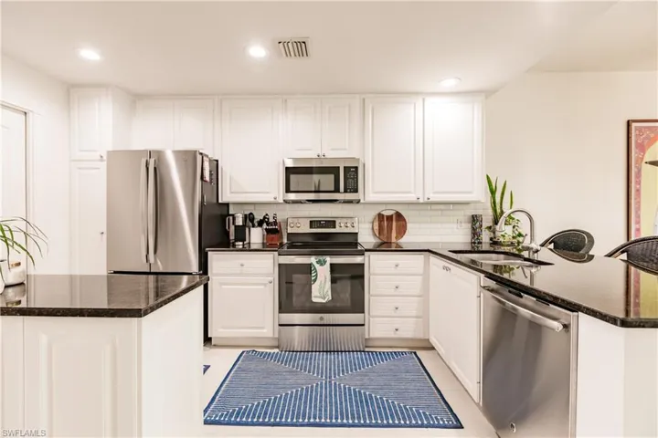 Kitchen with tasteful backsplash, stainless steel appliances, sink, kitchen peninsula, and light tile patterned floors