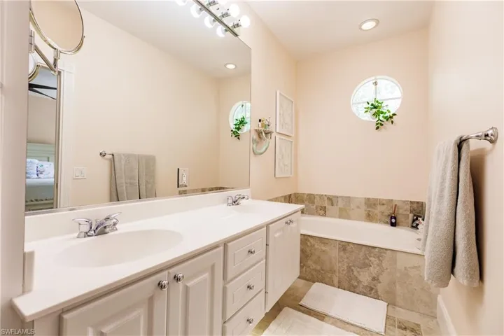 Bathroom with tile patterned flooring, dual vanity, and a relaxing tiled tub