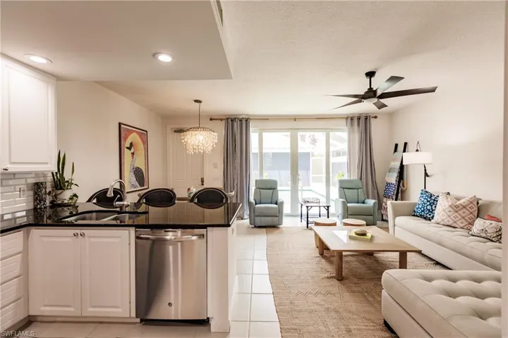 Kitchen with sink, white cabinetry, ceiling fan with notable chandelier, light tile patterned flooring, and dishwasher