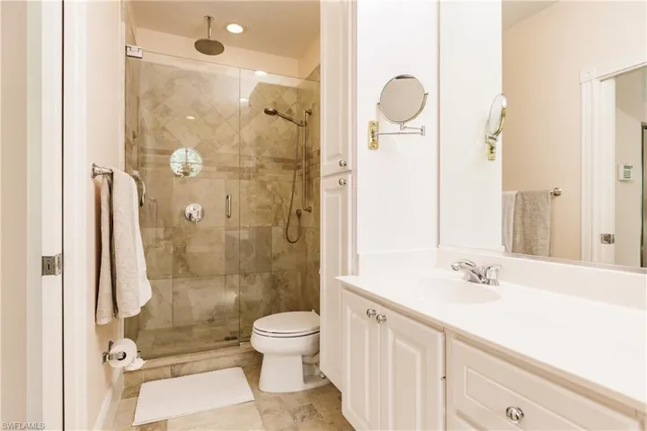 Bathroom with vanity, a shower with door, tile patterned flooring, and toilet