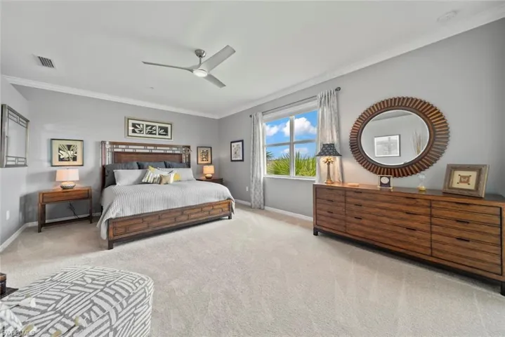 Carpeted bedroom with crown molding and ceiling fan