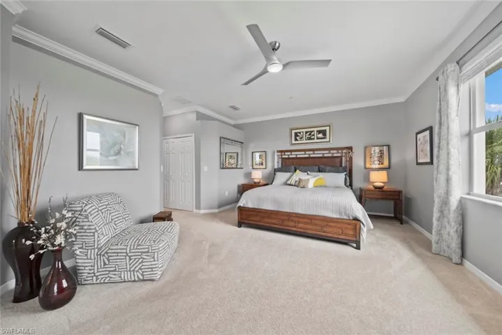 Bedroom with a closet, ornamental molding, light colored carpet, and ceiling fan