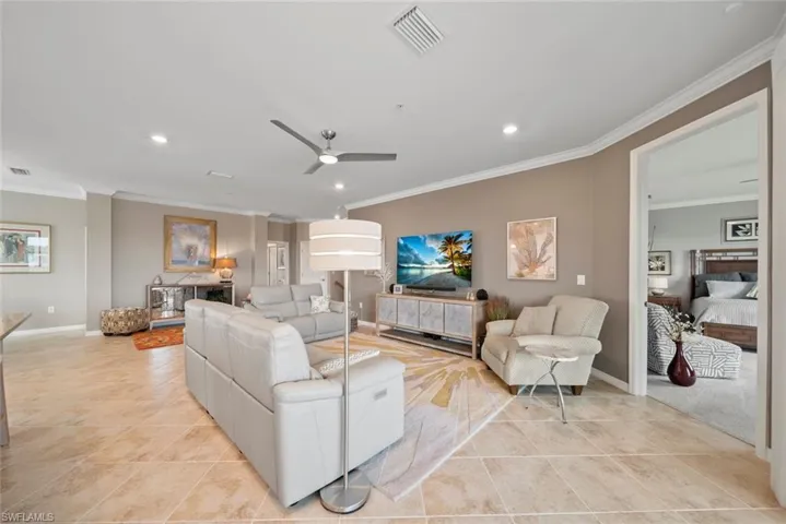 Living room with crown molding, light tile patterned floors, and ceiling fan