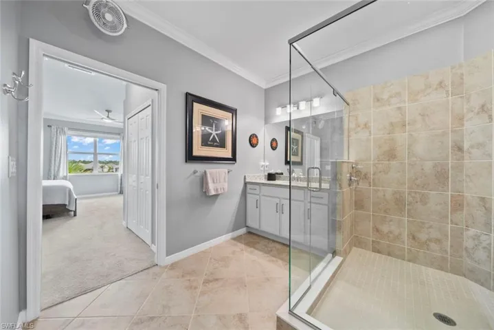 Bathroom with vanity, crown molding, tile patterned flooring, and a shower with door